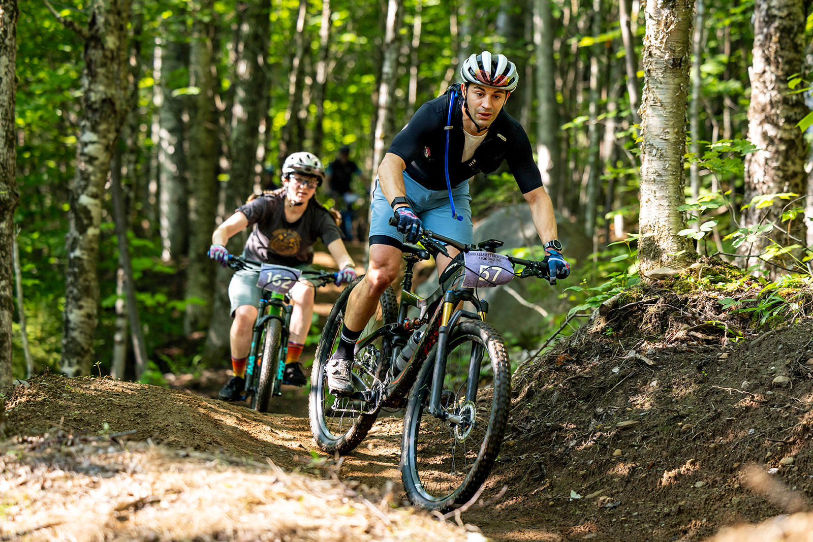 Two racers carving a berm through birch woods