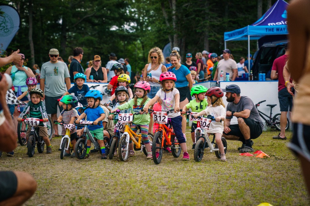 Young riders on balance bikes lined up at the start of the kids race