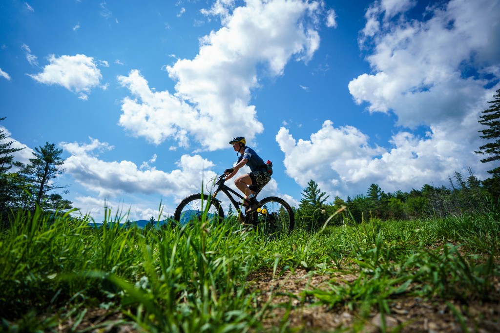 Rider crossing a grassy ridge under a big blue sky